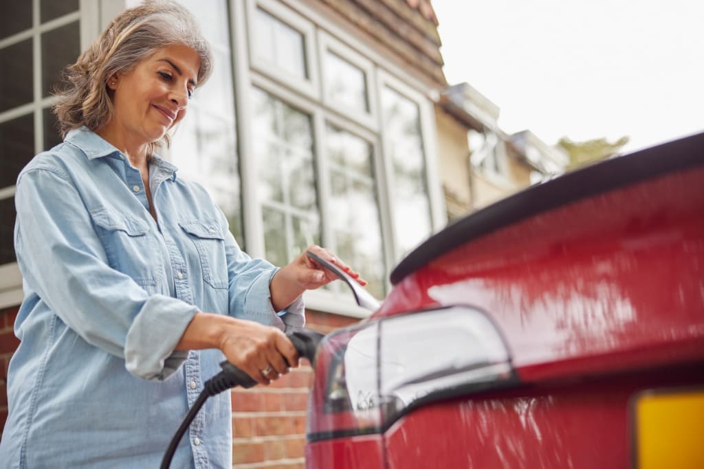 Conductrice branchant un véhicule électrique devant son logement