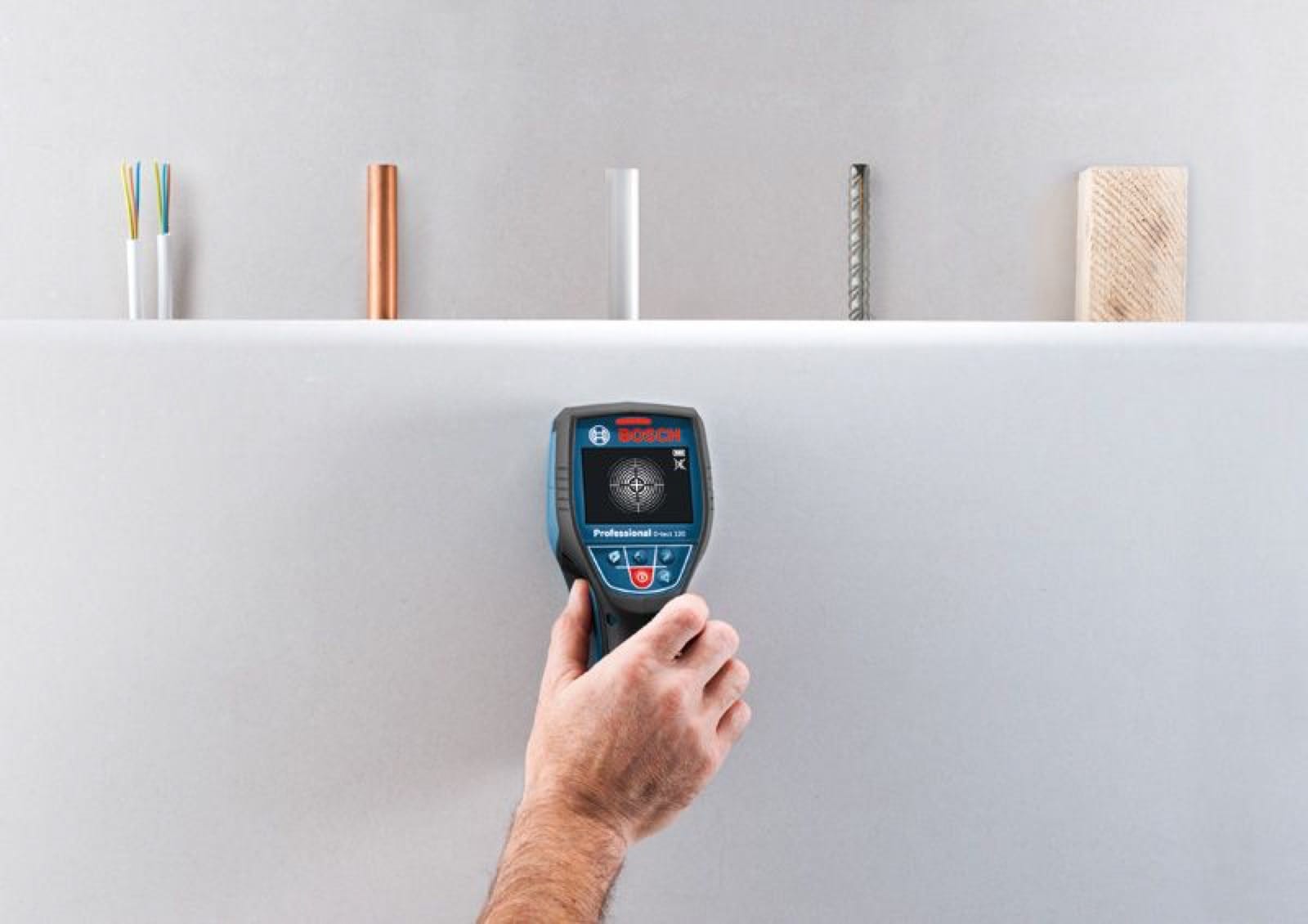 Détecteur Bosch D-tect 120 passé à la main sur un mur intérieur pour une détection de matériaux