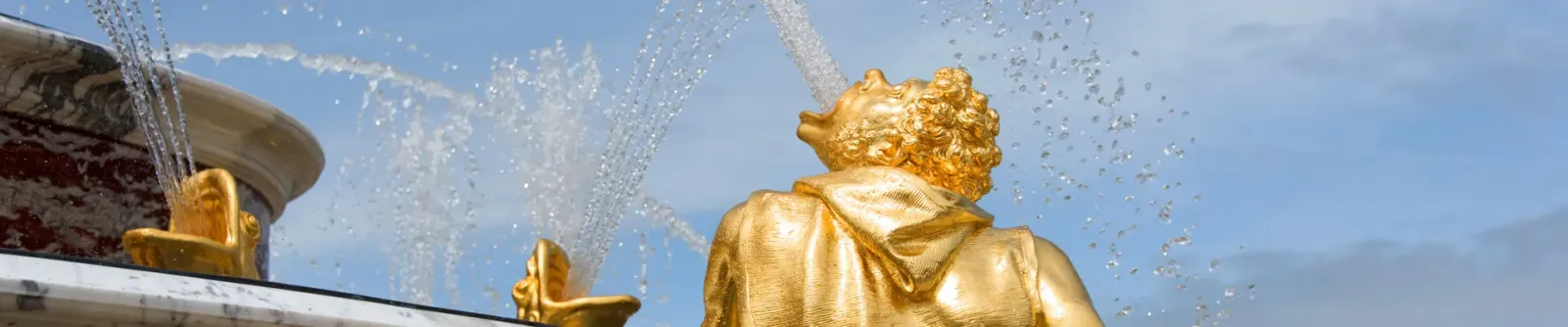 Statue dorée et jets d’eau dans les jardins du château de Versailles