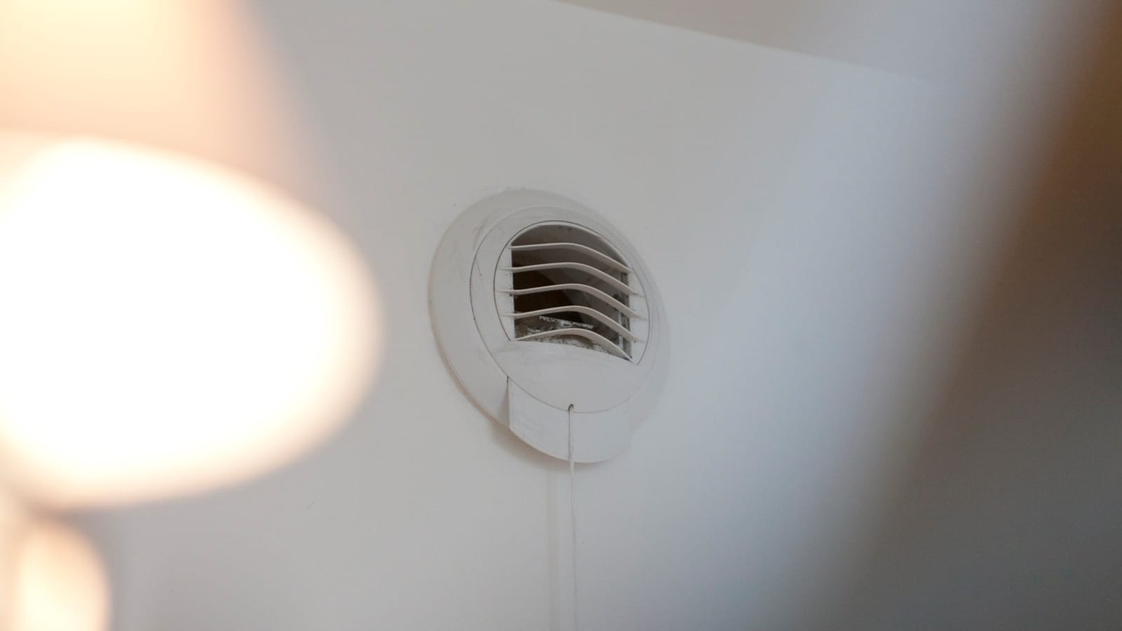 Bouche d’extraction de VMC ronde fixée au plafond, légèrement encrassée