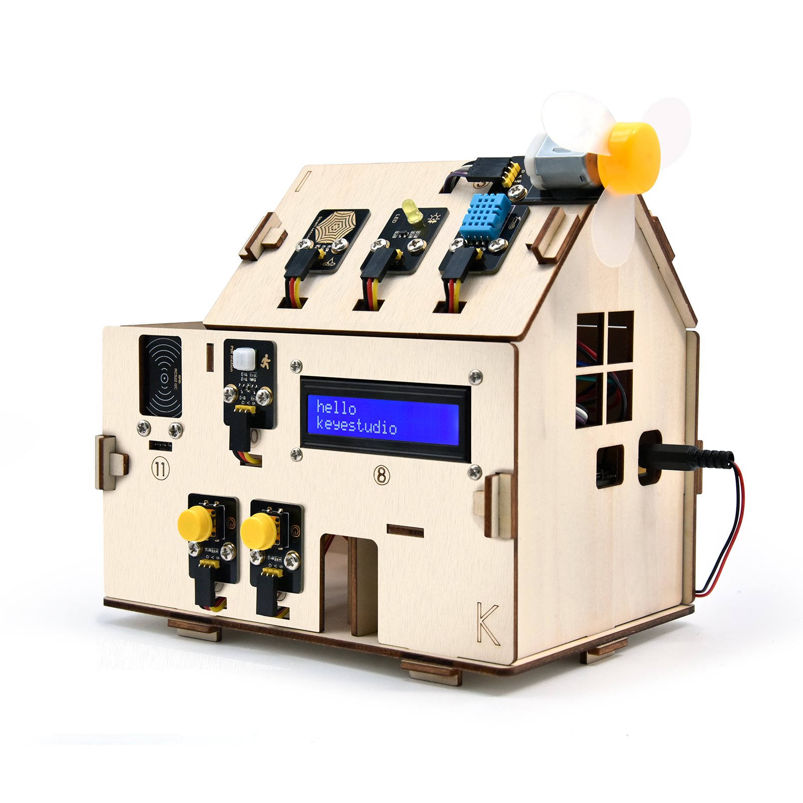 Maison miniature en bois équipée de composants électroniques dont un écran LCD affichant hello keyestudio, un ventilateur et des capteurs.