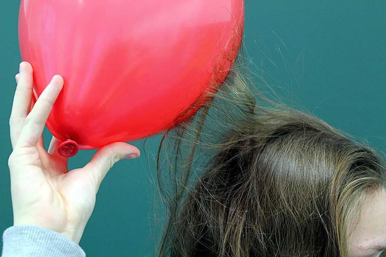 Cheveux attirés par un ballon rouge chargé d’électricité statique