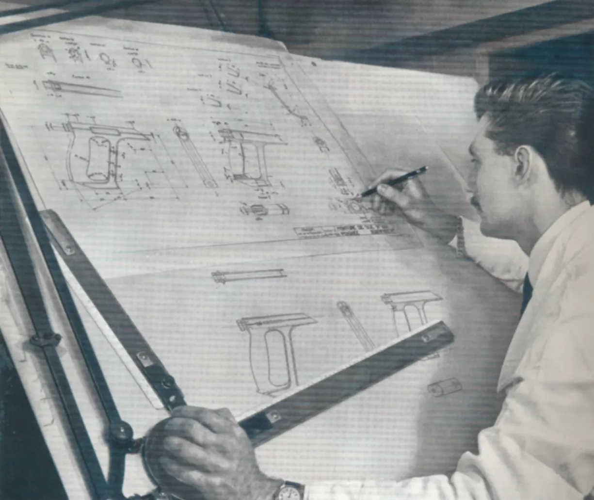 Photographie d’archive montrant un dessinateur travaillant sur des plans avec des outils Facom