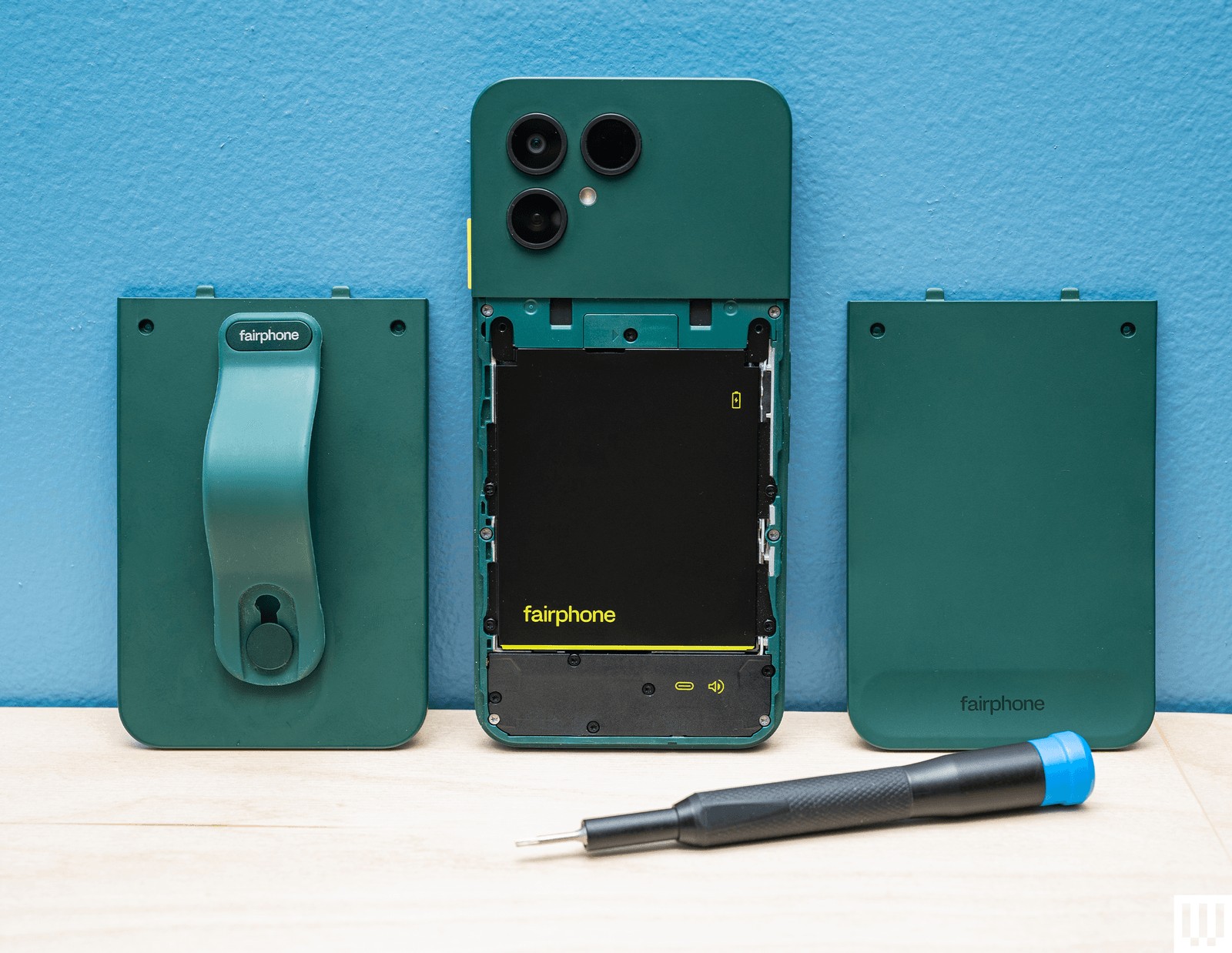 Fairphone vert démonté montrant la batterie amovible avec le dos retiré et un tournevis posé devant