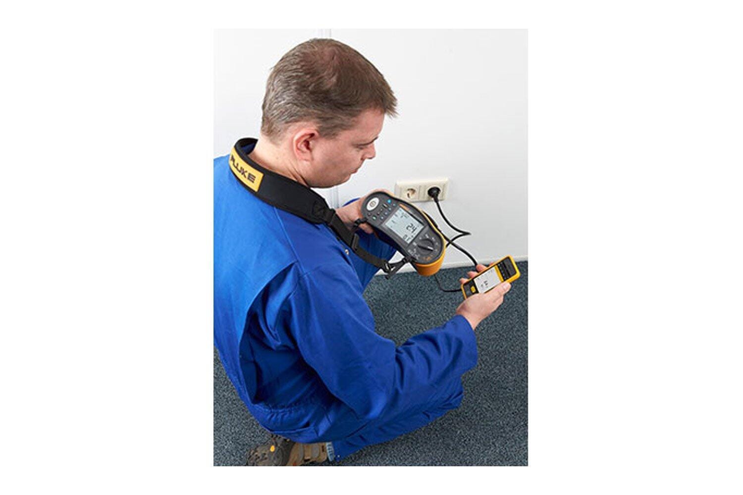Technicien utilisant un contrôleur d’installation Fluke 1664 FC avec un smartphone affichant le résultat