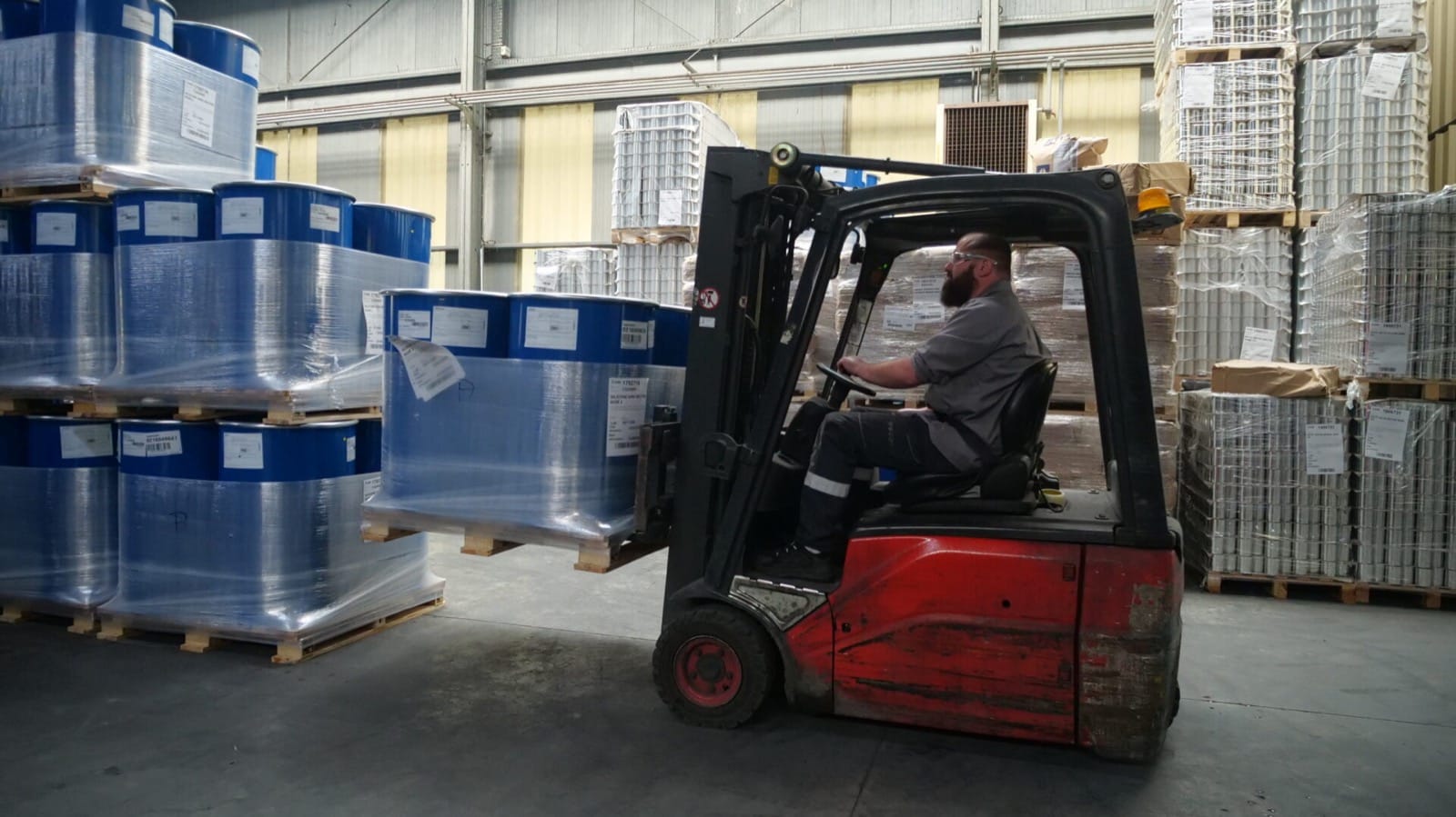Entrepôt industriel GEB avec chariot élévateur et fûts de matières premières sur palettes