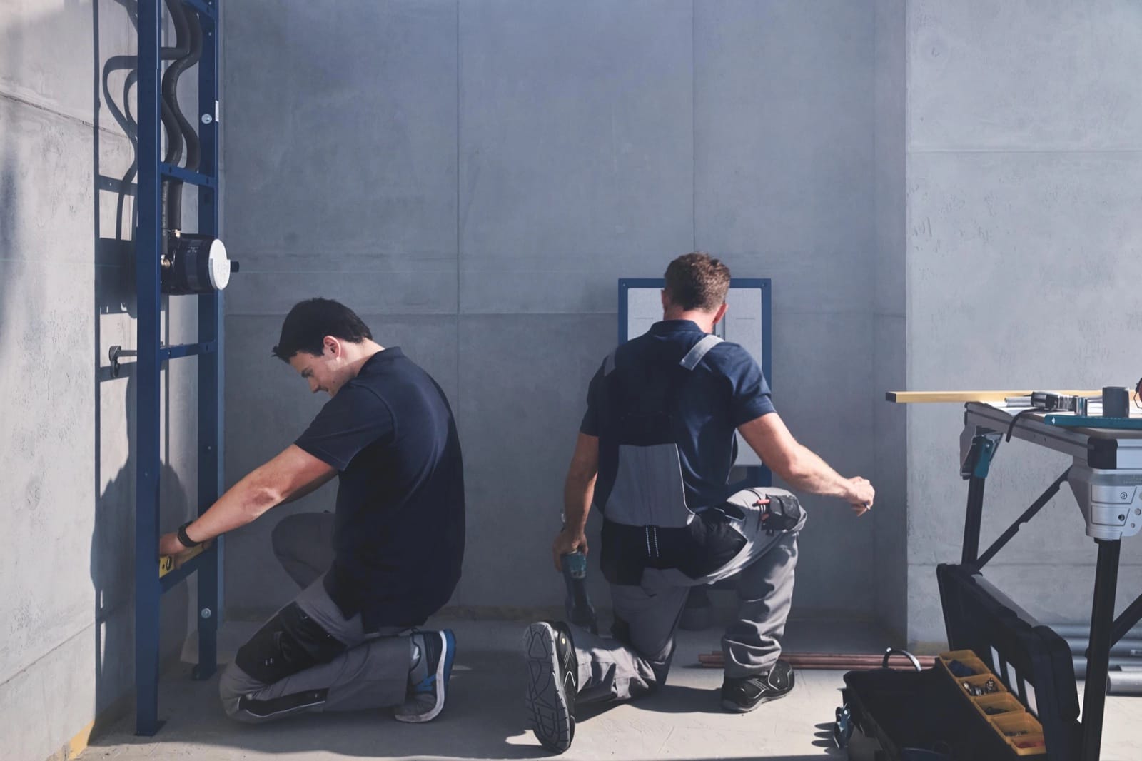 Deux installateurs travaillant ensemble à la pose d'une robinetterie dans une salle de bain
