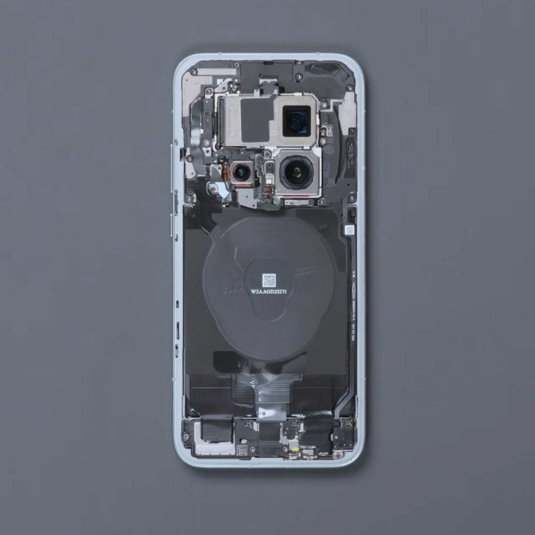Vue interne d’un smartphone démonté montrant les composants électroniques, les modules caméra et la bobine de charge sans fil sur fond gris.