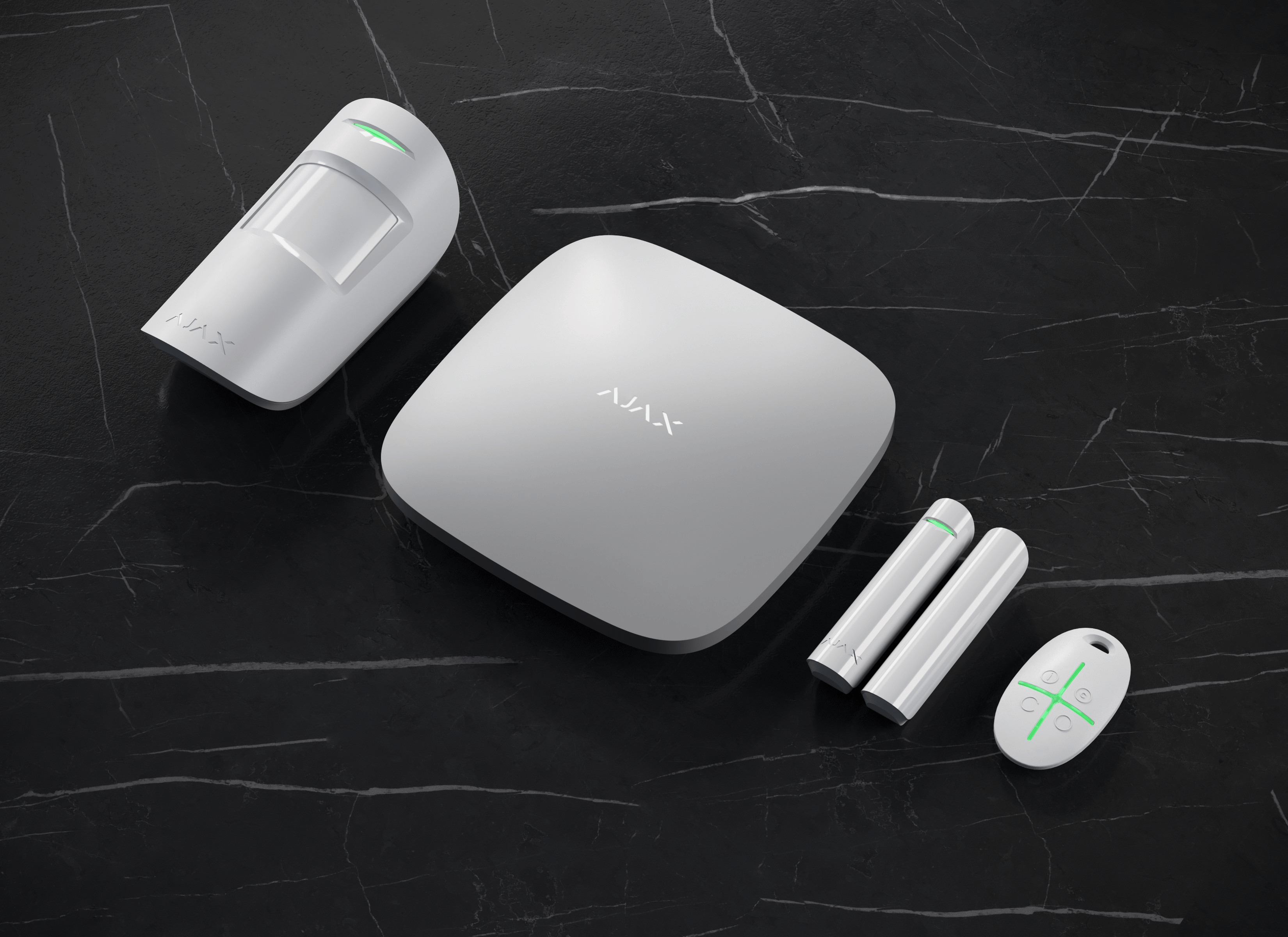 Kit d’alarme blanc de la marque Ajax posé sur une surface sombre, comprenant un hub, des détecteurs et une télécommande.