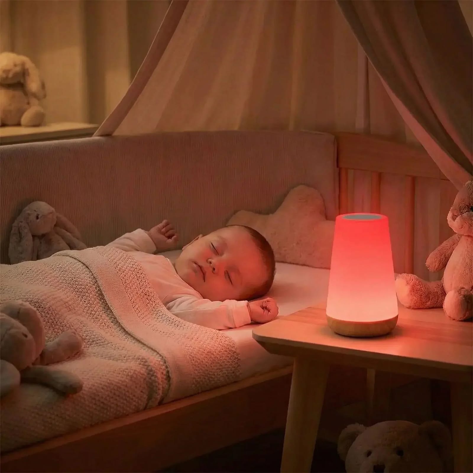 Bébé endormi dans son lit, une veilleuse cylindrique diffuse une lueur rouge tamisée depuis la table de nuit