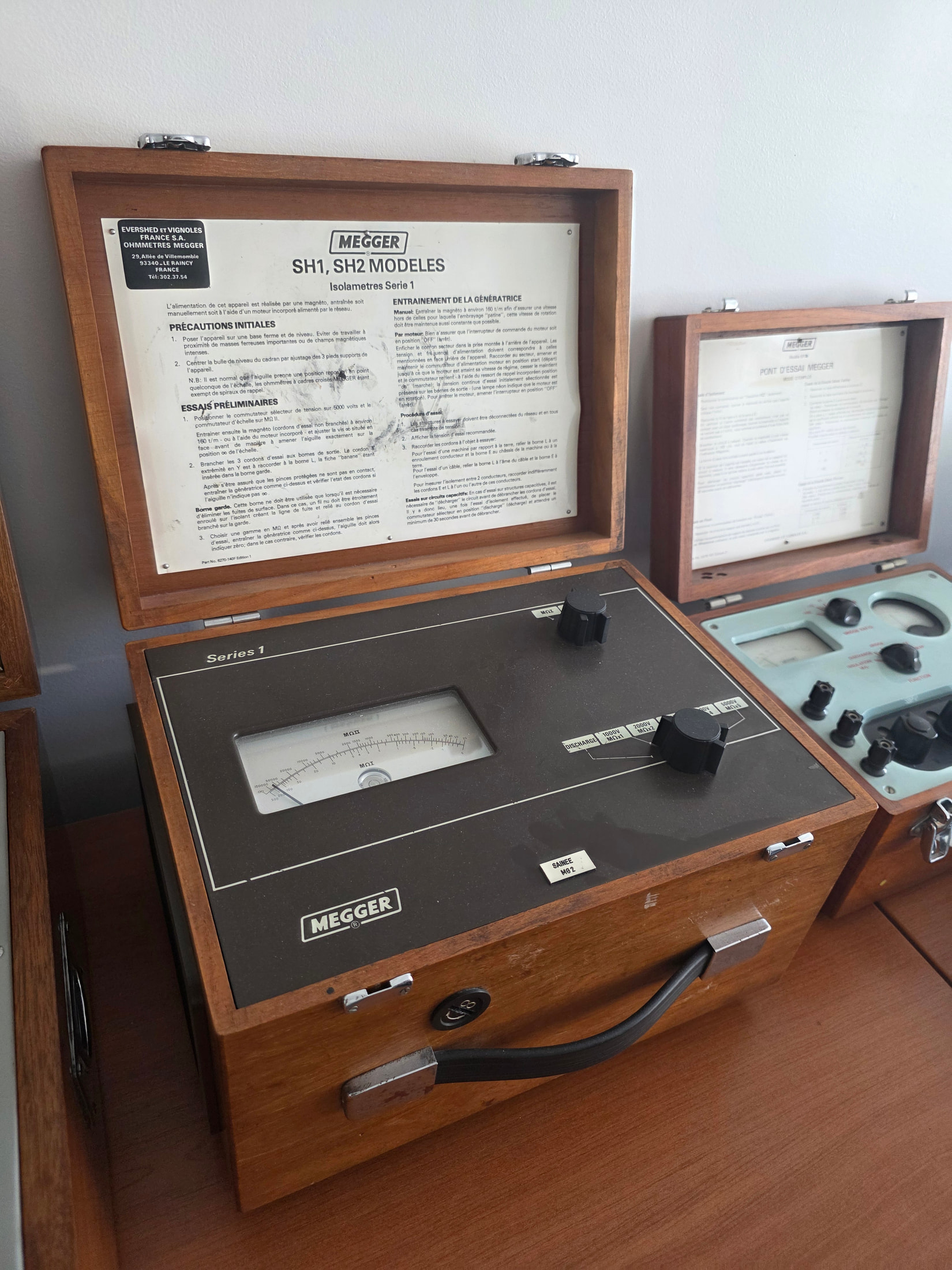 Collection d’appareils de mesure anciens dans des coffrets de bois au showroom Megger