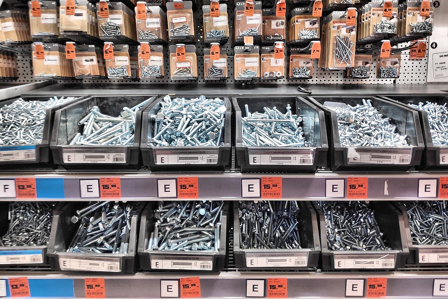Rayon de vis et de quincaillerie dans un magasin de bricolage, avec des bacs et des paquets suspendus