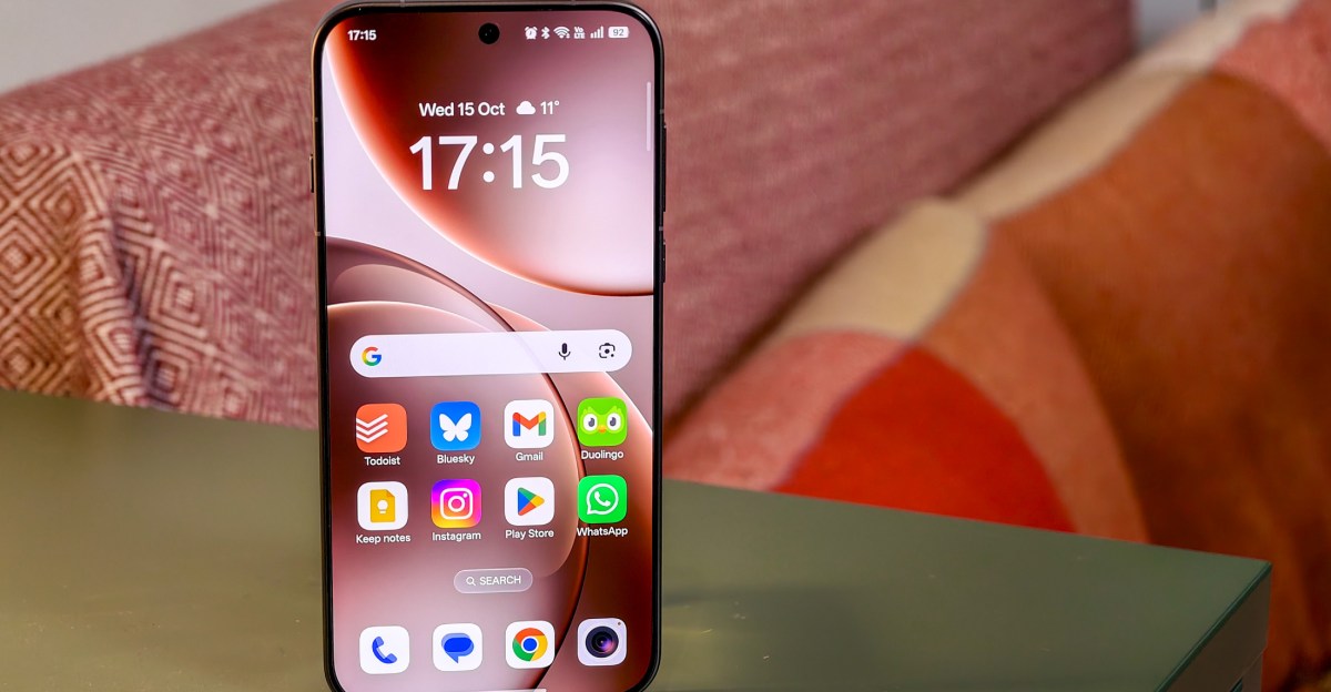 Un smartphone est posé verticalement sur une table, son écran affichant l’heure et des icônes d’applications.