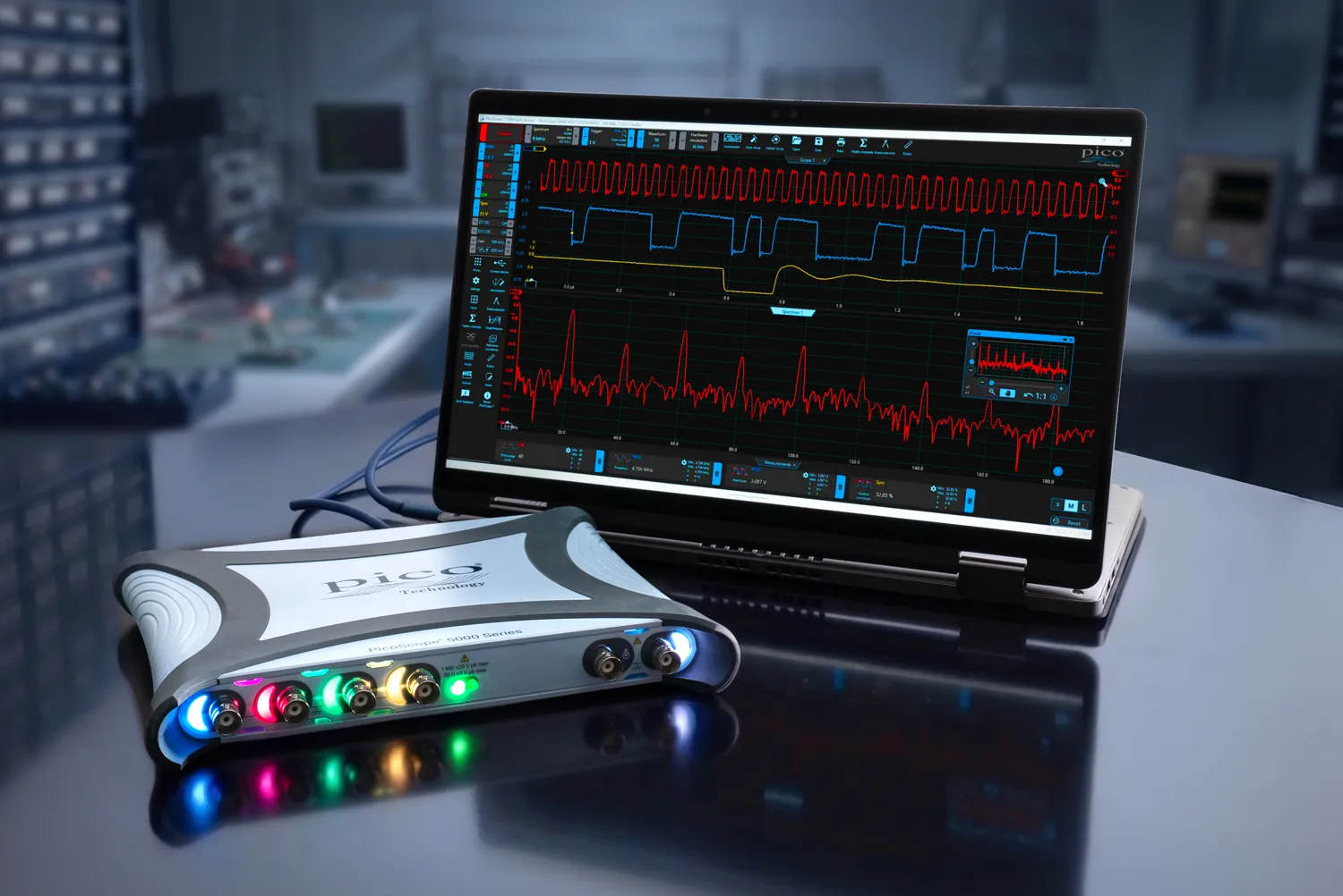 Un oscilloscope USB Pico Technology PicoScope 5000 Series connecté à un ordinateur portable affichant plusieurs formes d’onde colorées sur son écran.