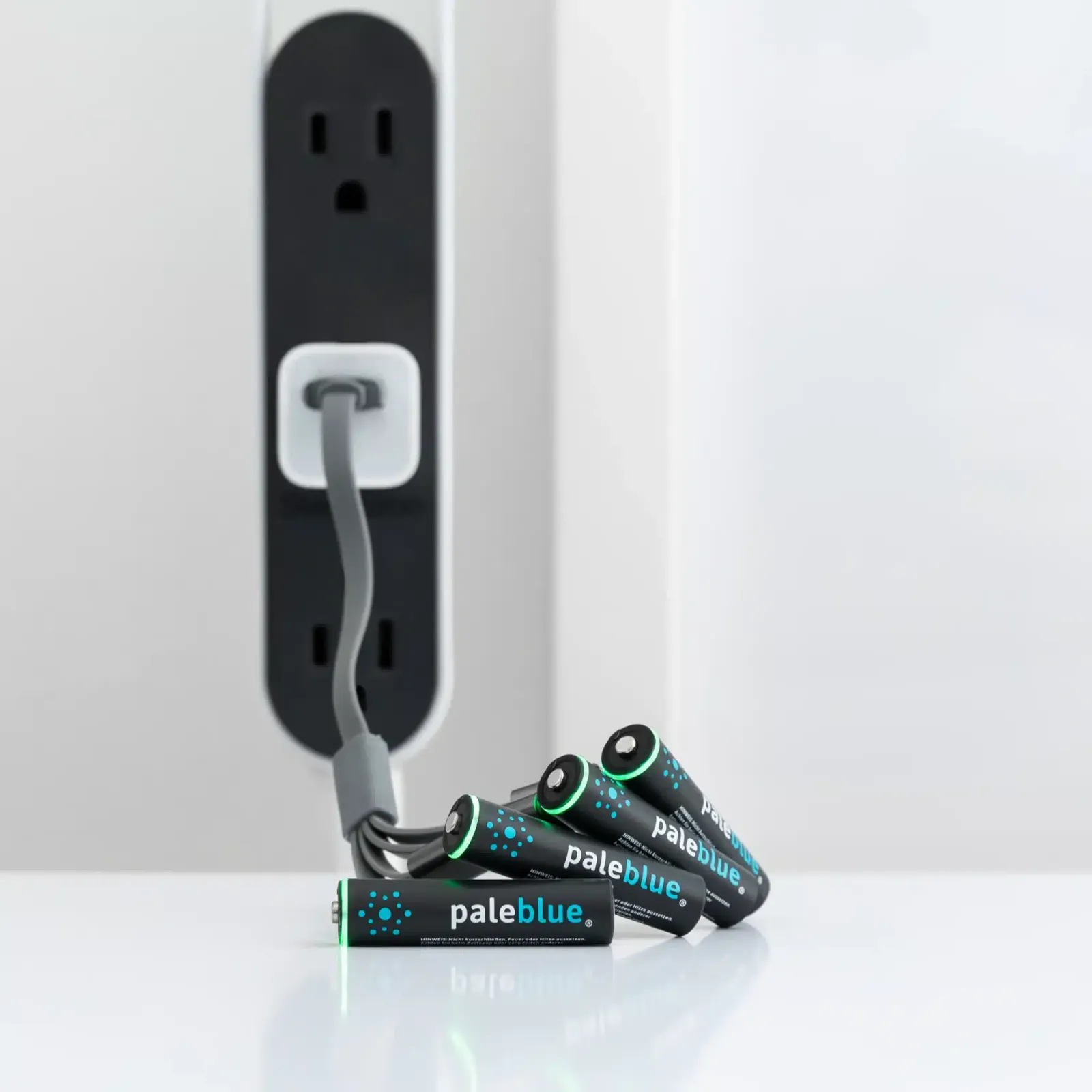 Quatre piles AAA rechargeables Pale Blue reliées à un câble USB-C multiple branché sur une prise