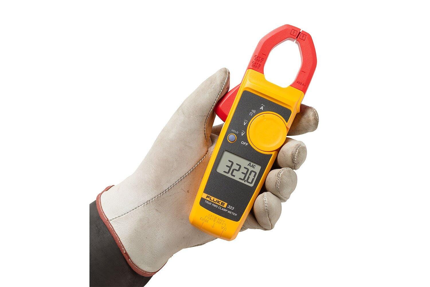 Pince ampèremétrique Fluke 323 tenue à la main, avec mâchoire ouverte