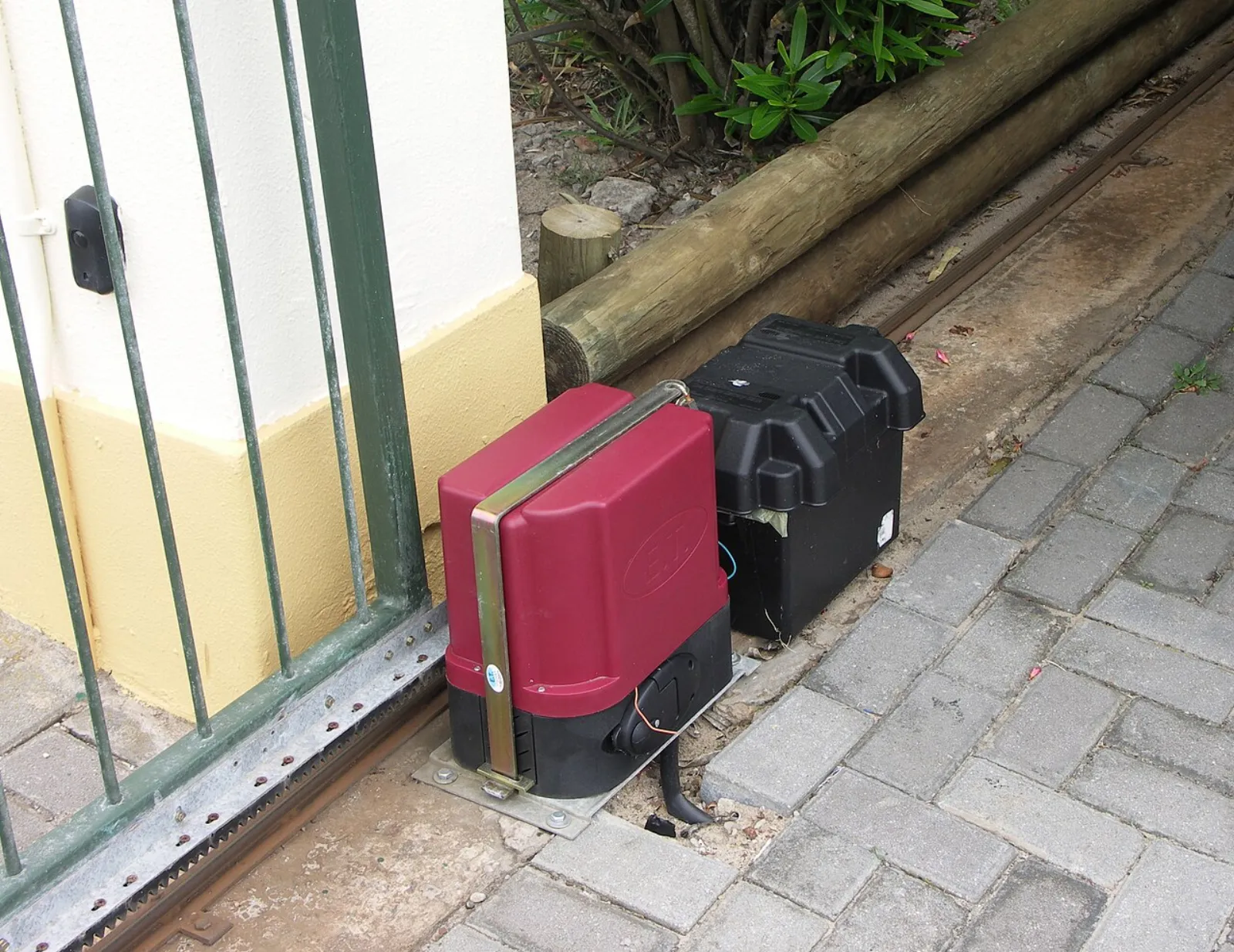 Motorisation installée au pied d’un portail coulissant avec son rail