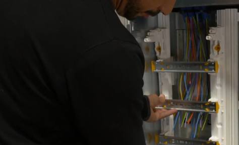 Électricien devant un tableau électrique en cours d'équipement