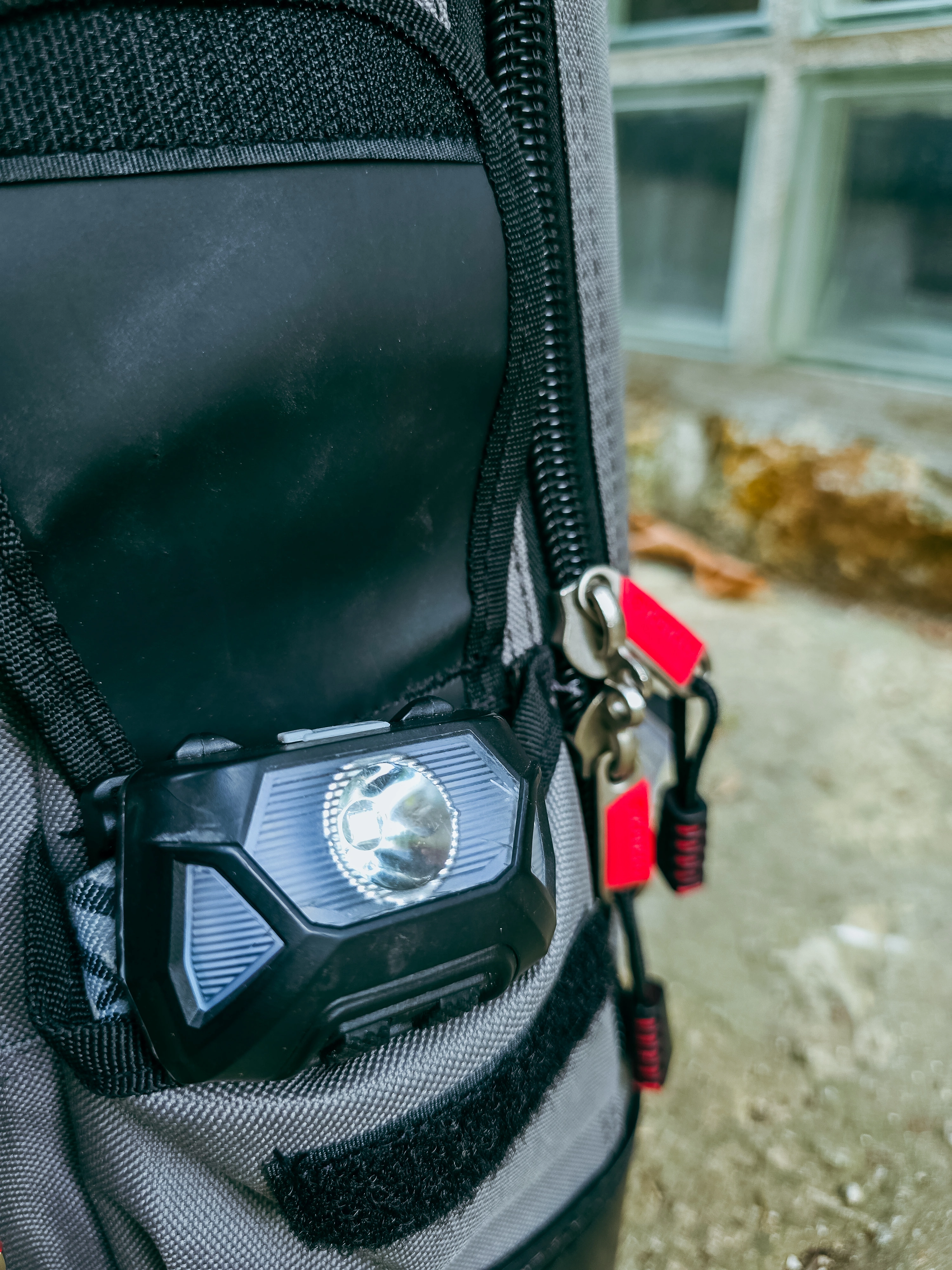 Lampe frontale glissée sur l’extérieur d’un sac gris à fermetures rouges