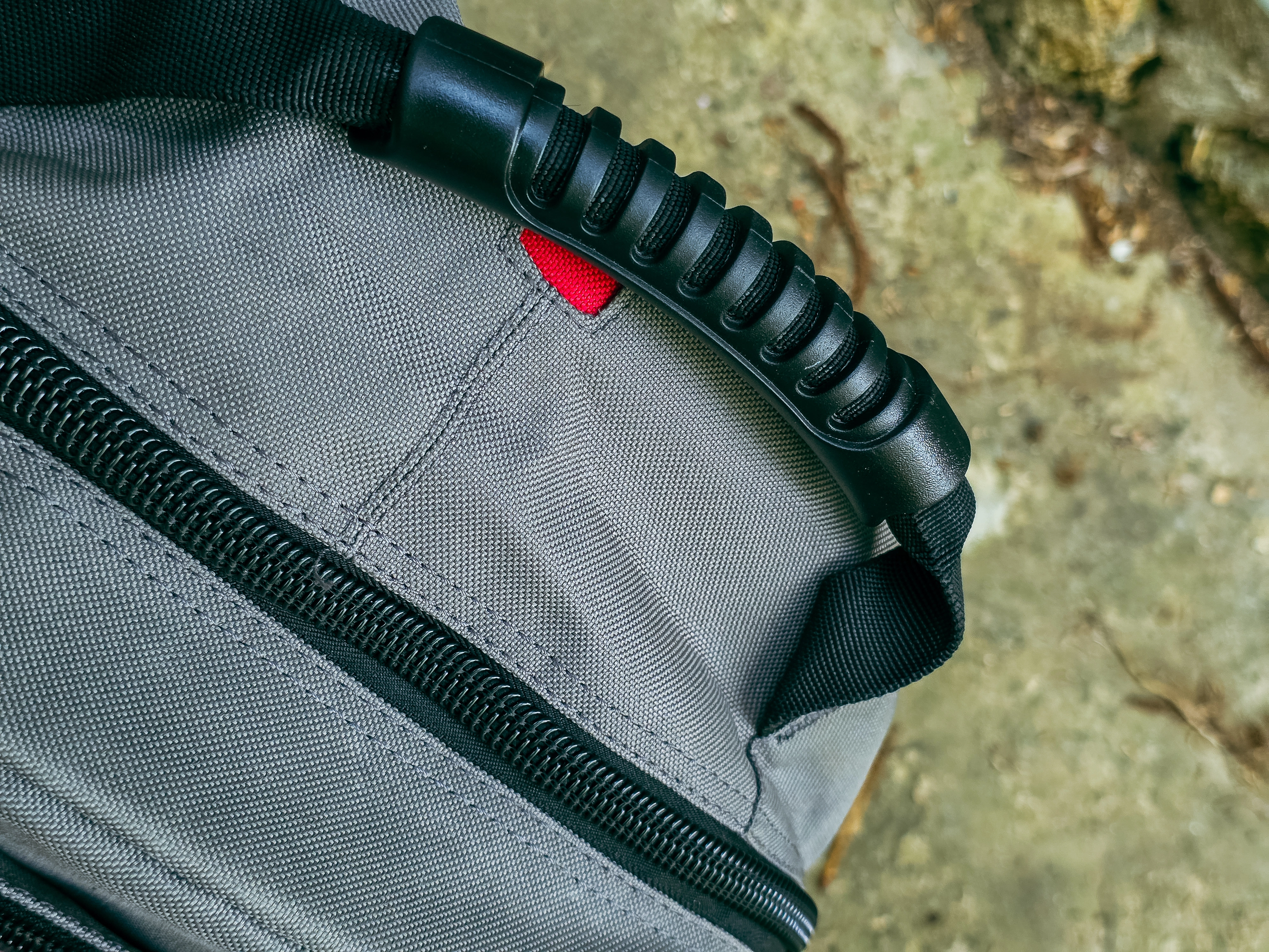 Gros plan de la poignée noire nervurée sur le dessus d’un sac C.K Magma gris