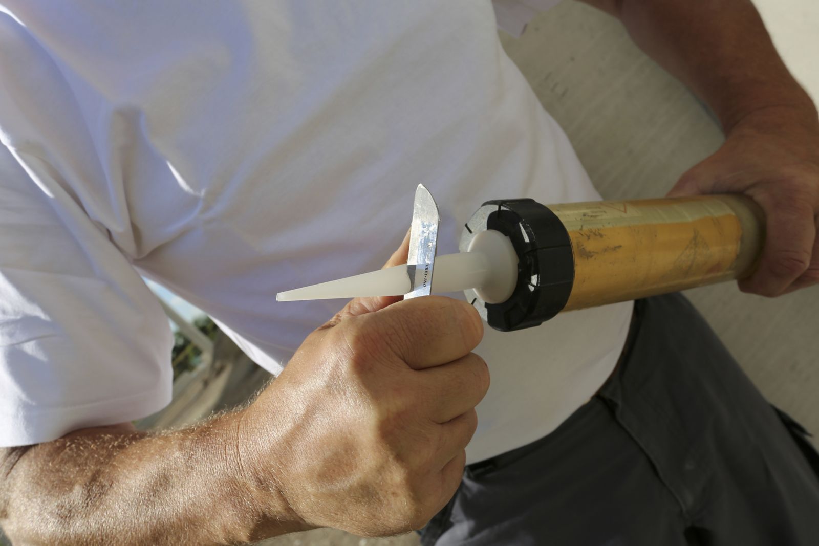 Artisan coupant l’embout d’une cartouche de mastic avant application
