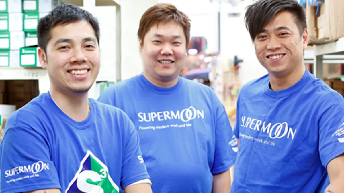 Trois collaborateurs en polo bleu Supermoon dans une agence ou un entrepôt