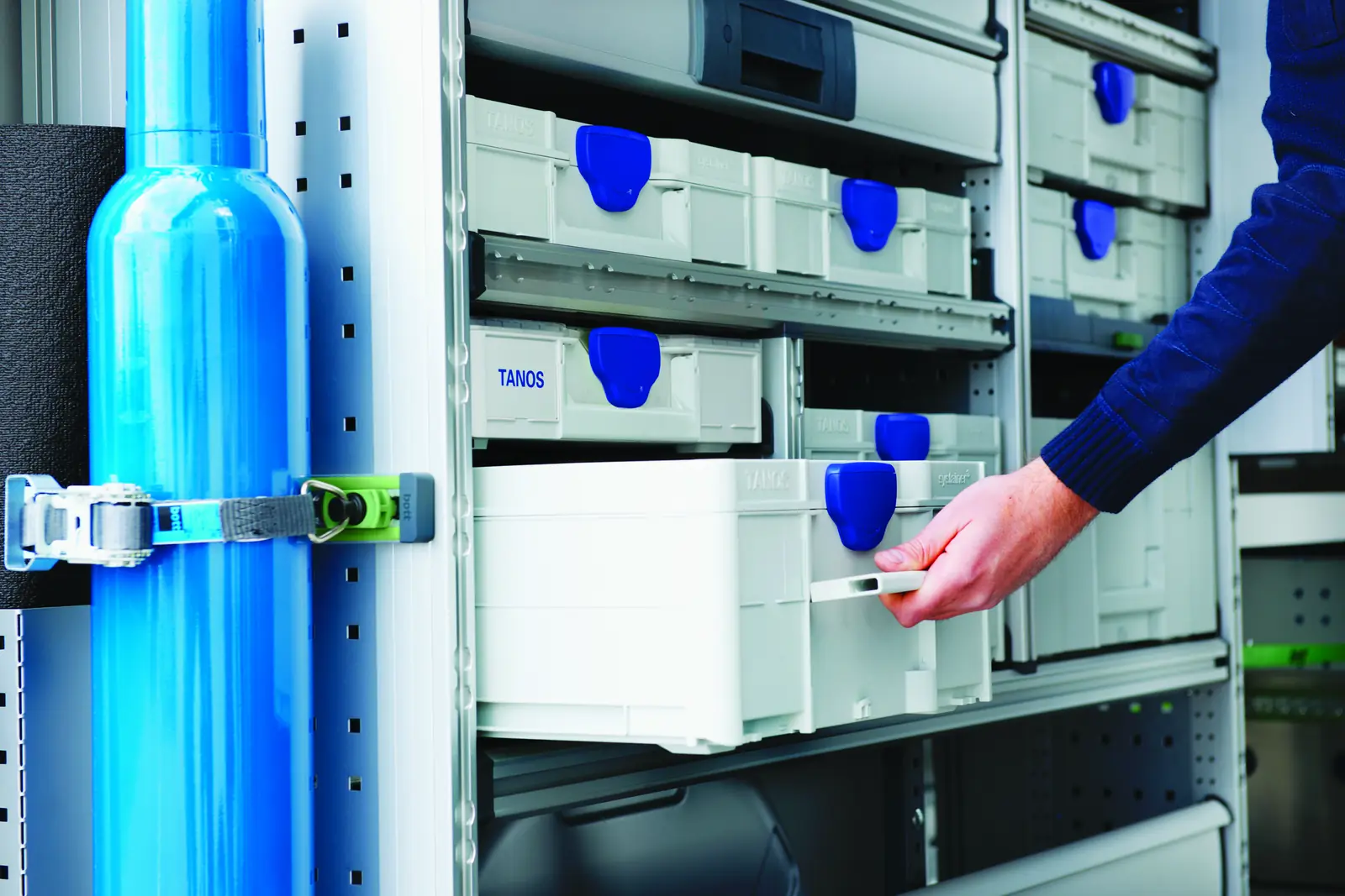Systainer gris clair avec fermoirs bleus rangés sur des étagères de stockage