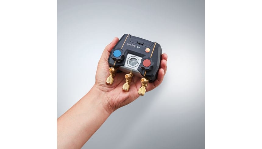 Manifold Testo 550i tenu dans une main, avec deux vannes et trois raccords visibles