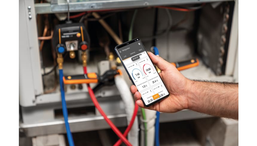 Smartphone affichant les mesures du Testo 550i près d’un manifold raccordé à une installation frigorifique