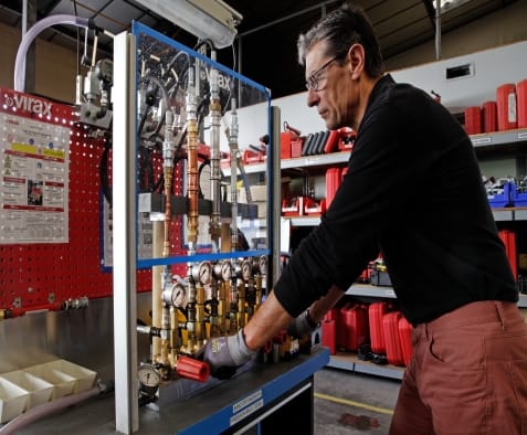 Technicien Virax testant un ensemble de raccords et manomètres sur un banc d'essai réseau