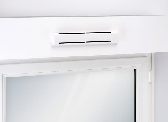 Entrée d’air hygroréglable Aereco EAH² au-dessus d’une fenêtre blanche