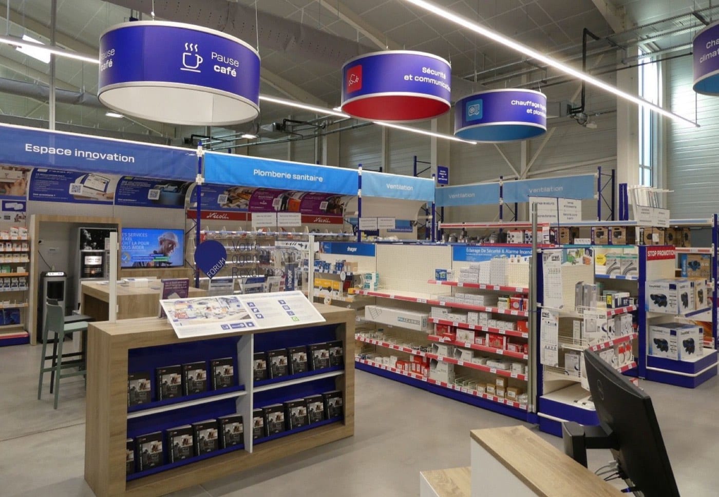 Intérieur d'une agence Rexel avec libre-service, rayons signalés et espace conseil