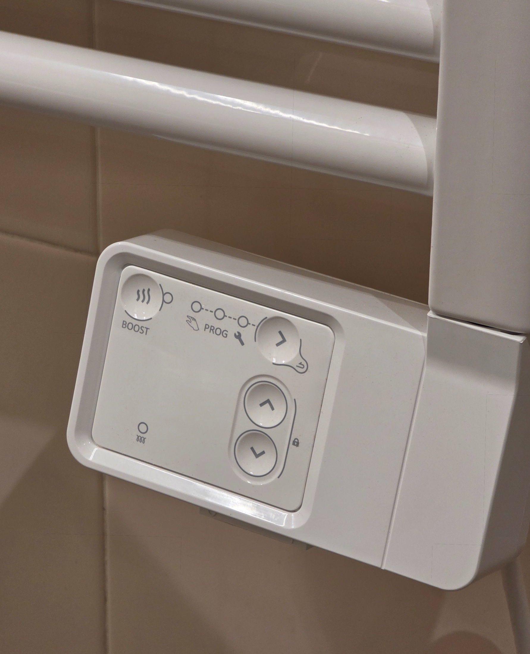 Gros plan sur le boîtier de commande blanc d’un sèche-serviettes avec boutons et flèches directionnelles