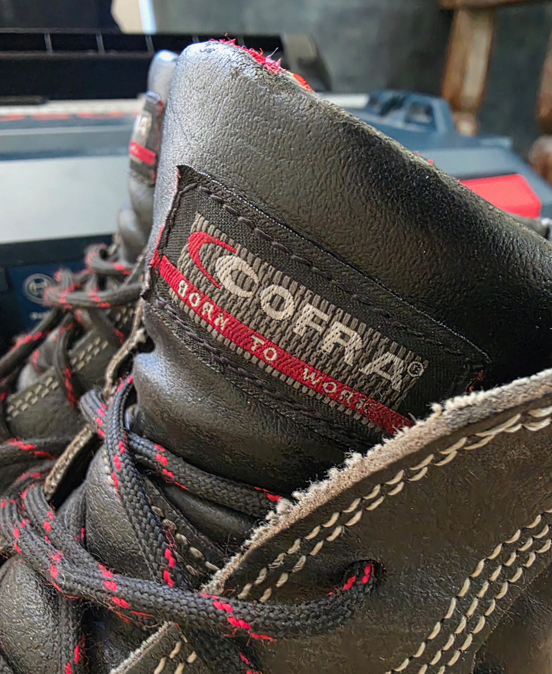 Gros plan sur une botte de sécurité Cofra noire à lacets rouges avec l’étiquette Born to Work