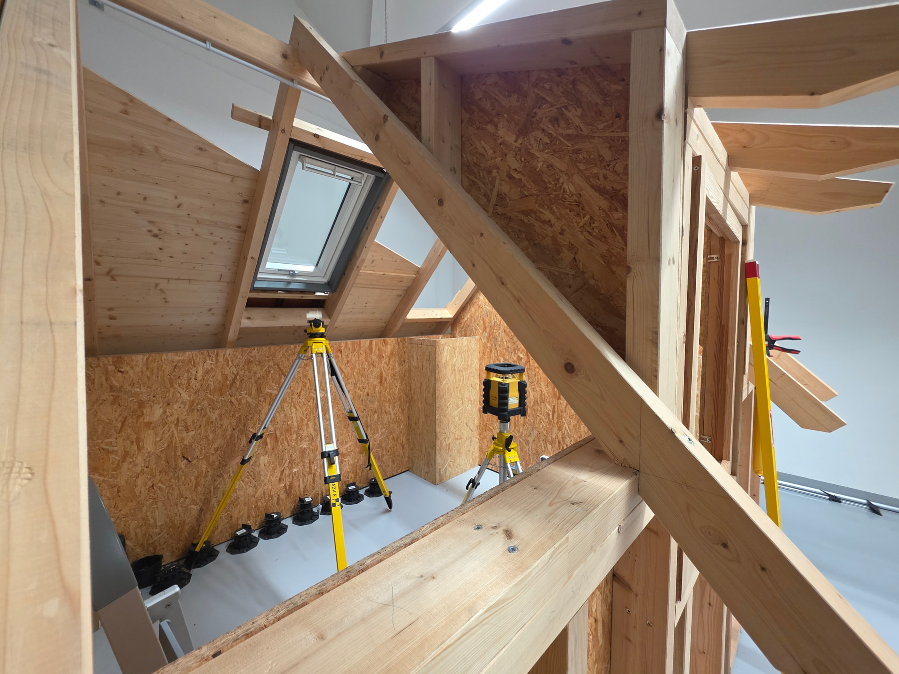 Maquette de maison à ossature bois avec un laser rotatif et un niveau laser STABILA posés sur trépieds
