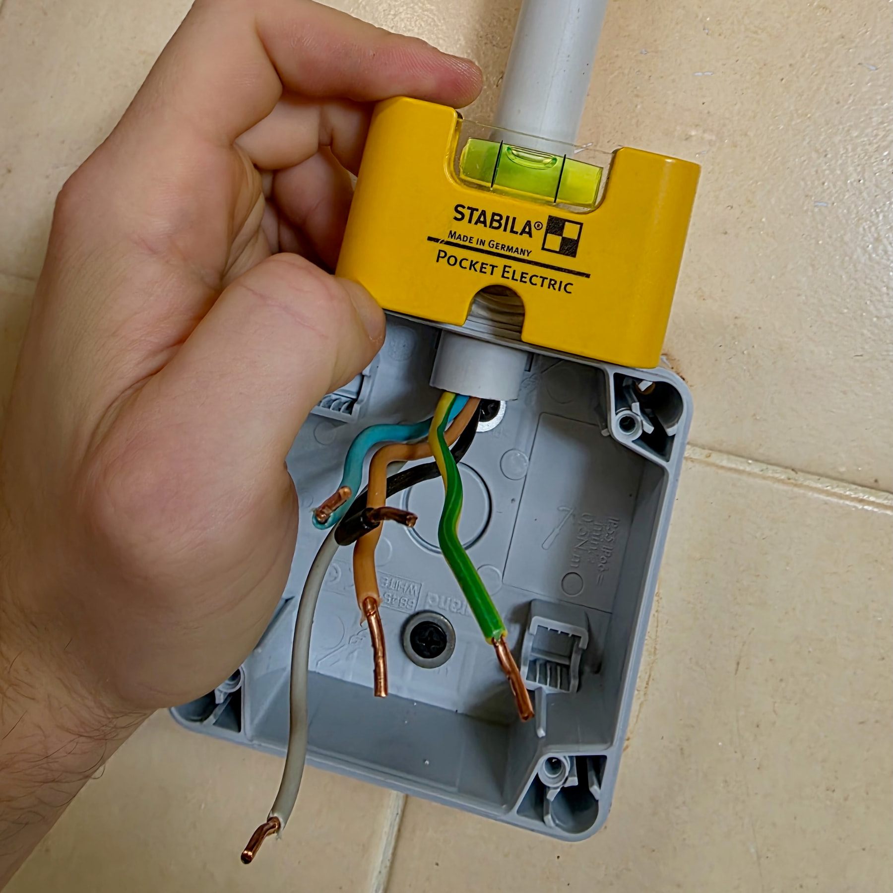 Boîtier de prise mis au niveau avec un niveau STABILA Pocket Electric posé dessus
