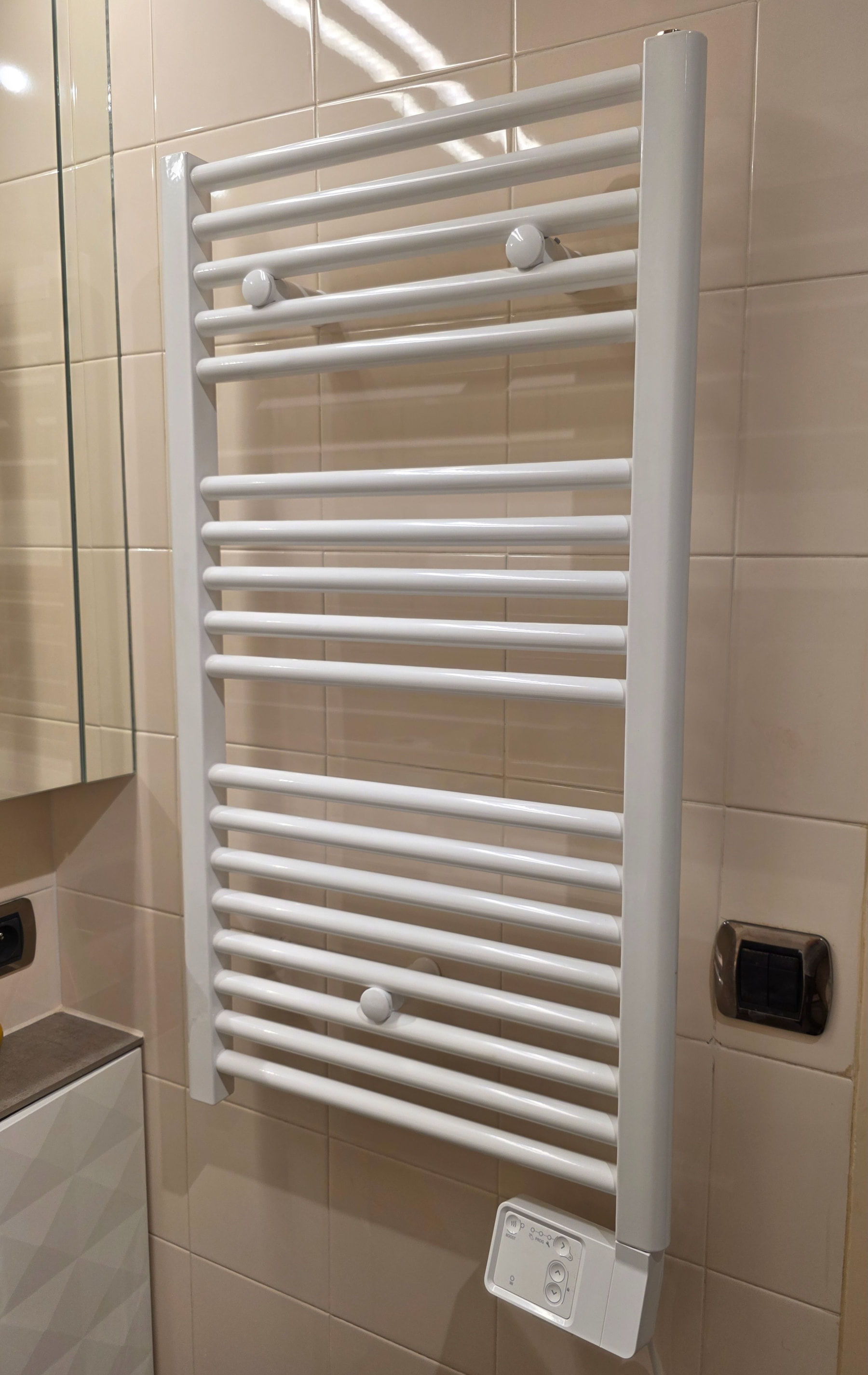 Sèche-serviettes électrique installé dans une salle de bain carrelée