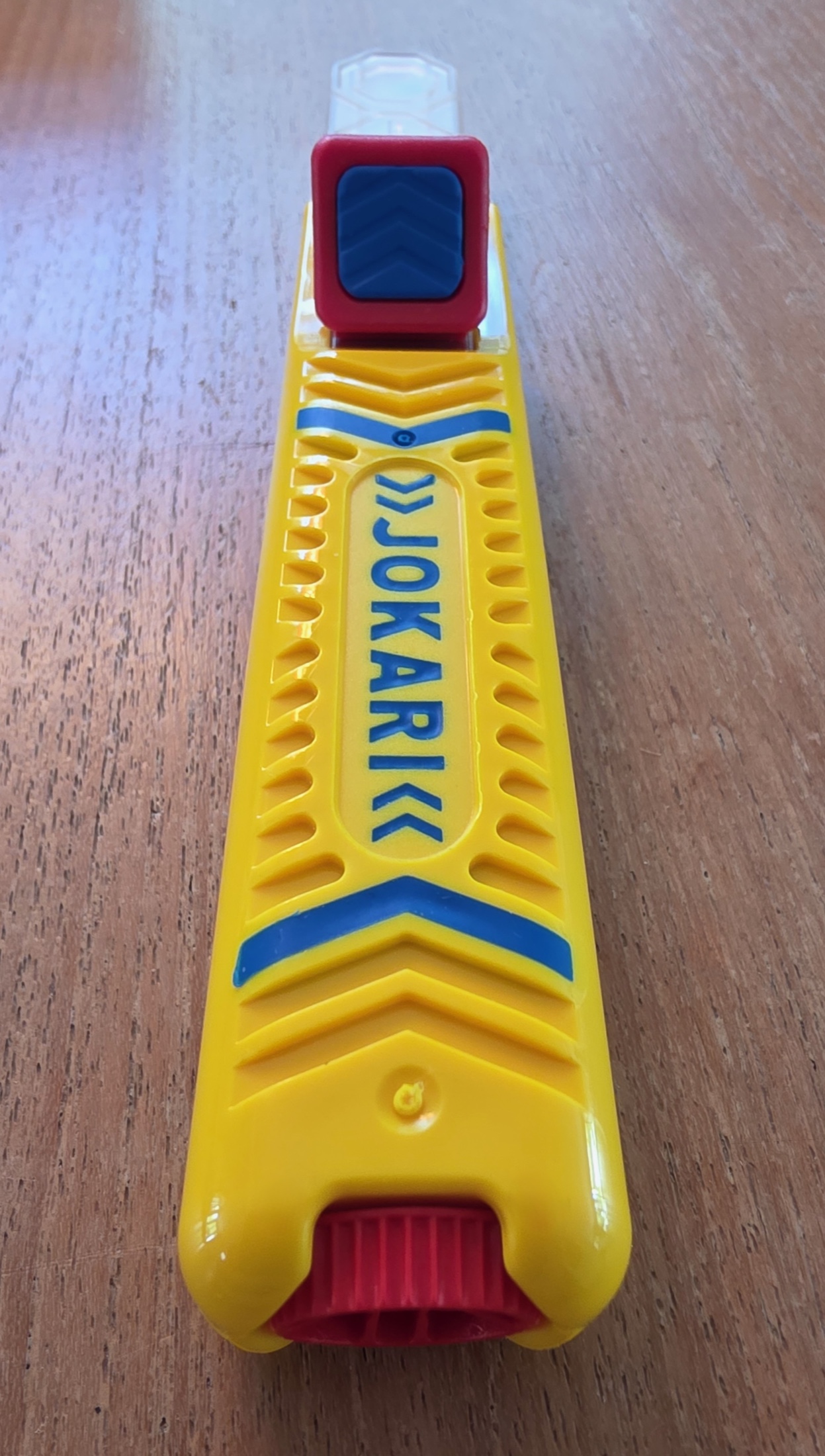 Vue de dessus du manche jaune du dénudeur Jokari No. 28H avec le logo bleu et le bouton rouge